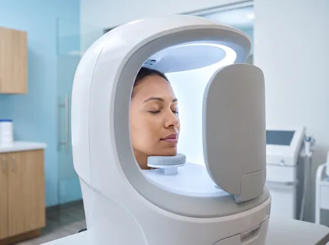 A patient inside a facial imaging booth for skin analysis