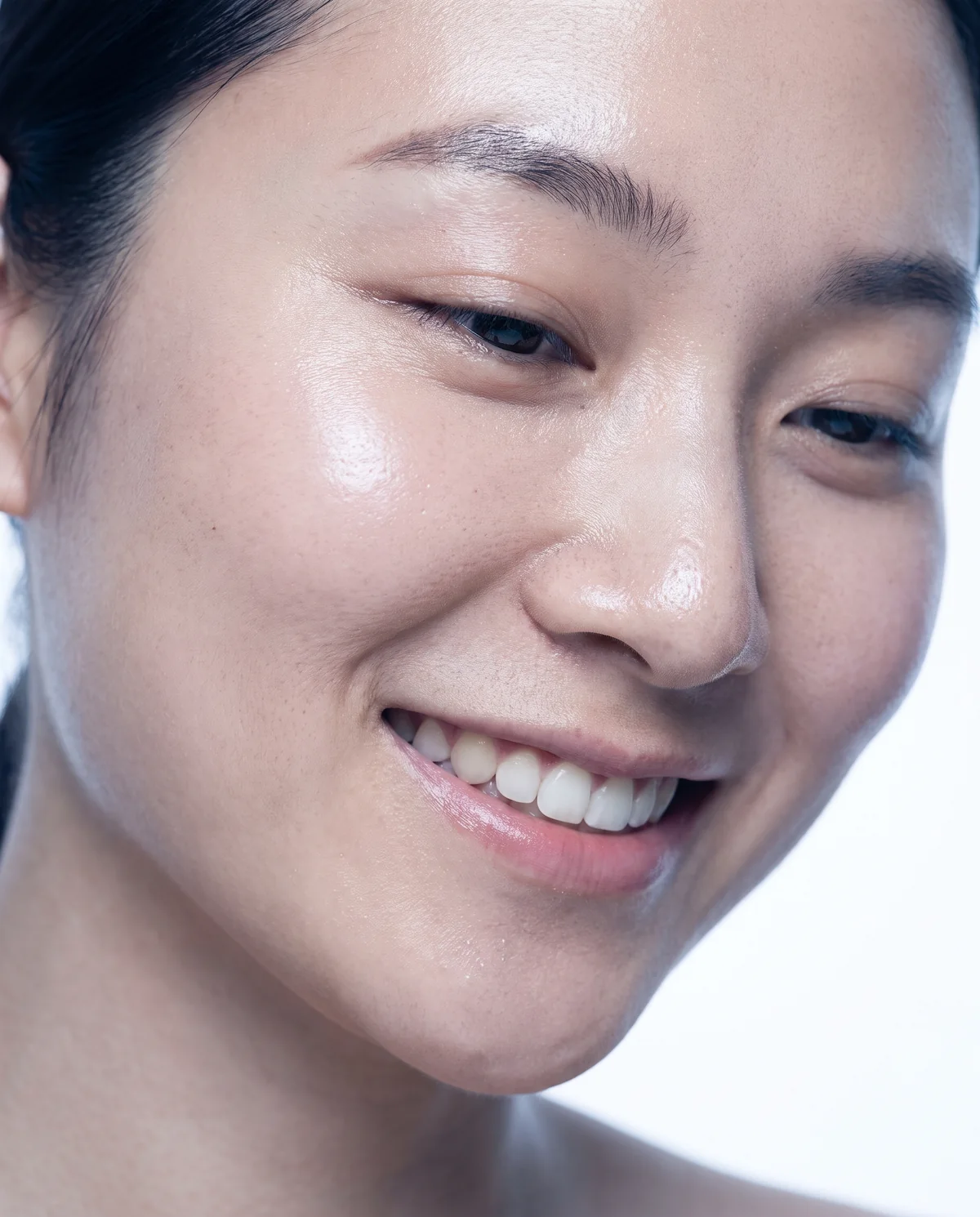 Close-up of a smiling woman's cheek and eye on a white background