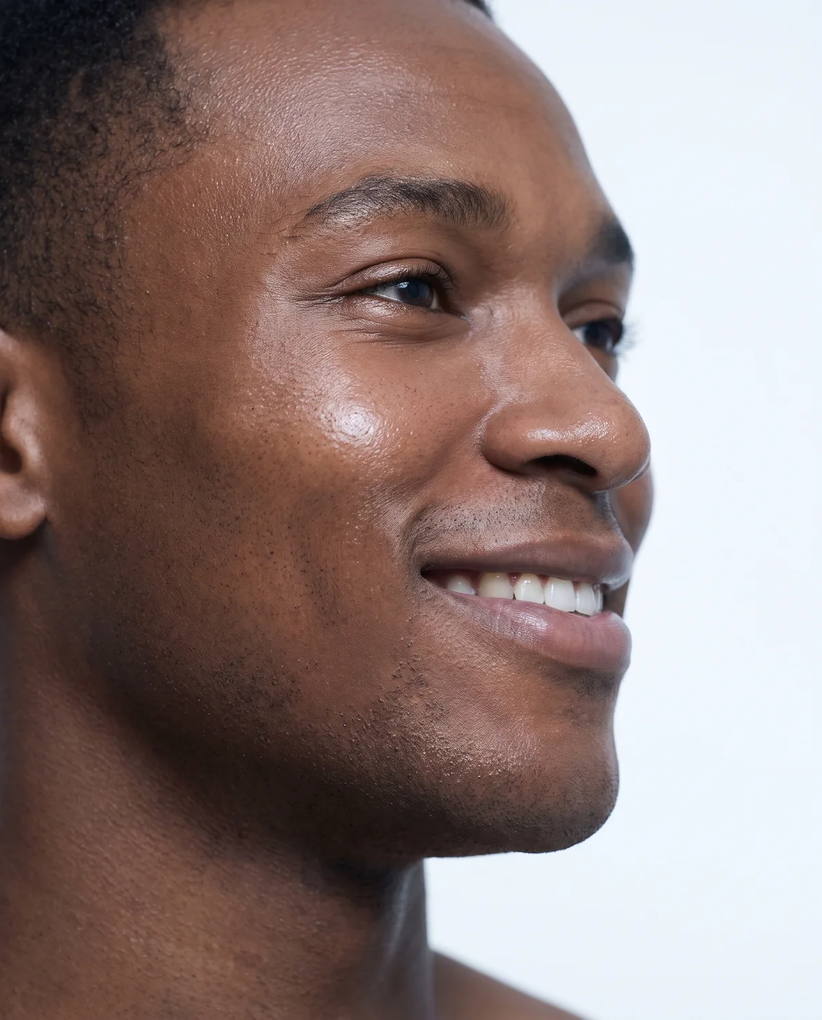Side profile close-up of a smiling man on a white background