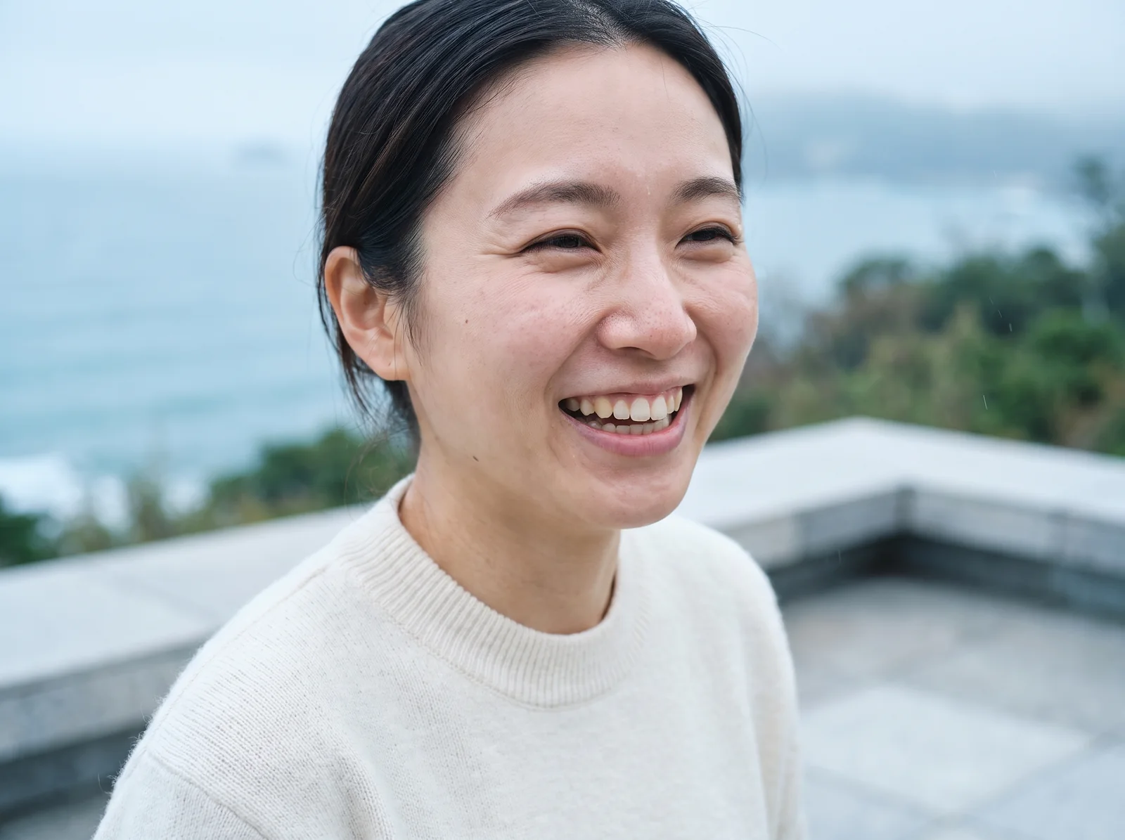 Portrait of a woman outdoors in bright cool daylight, glowing skin, laughing