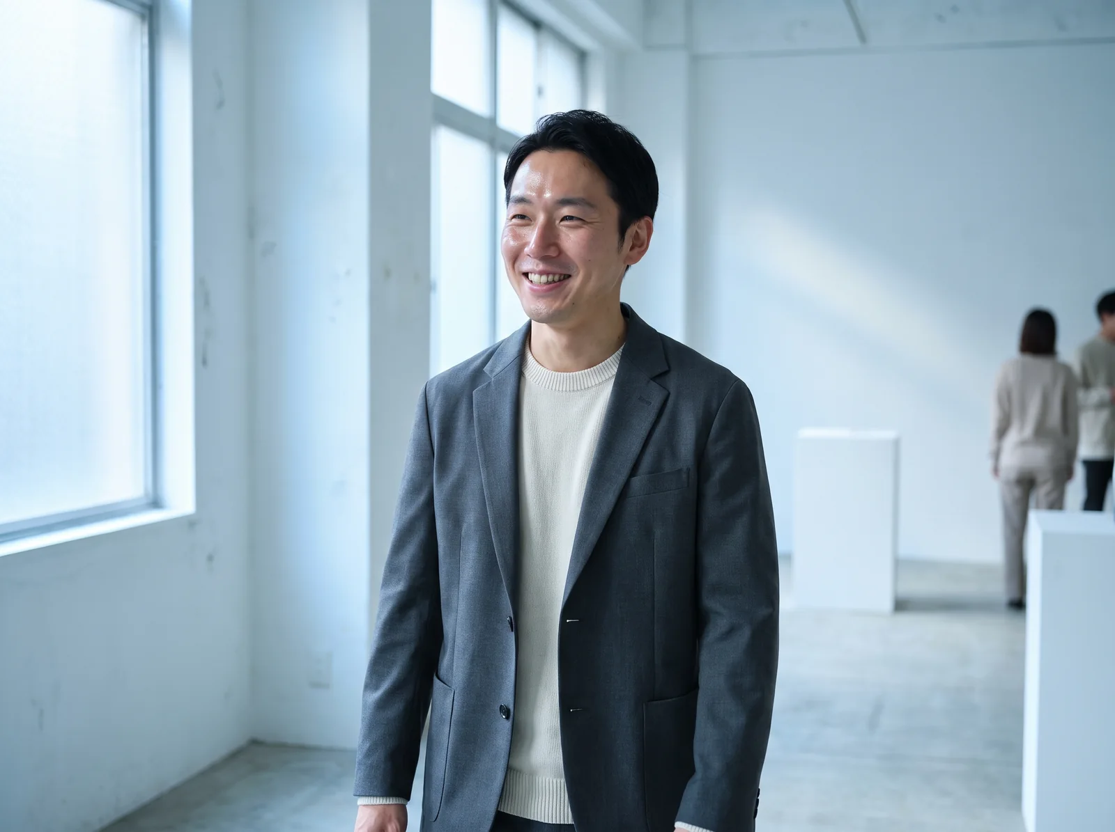A man walking through a bright white gallery with blank walls